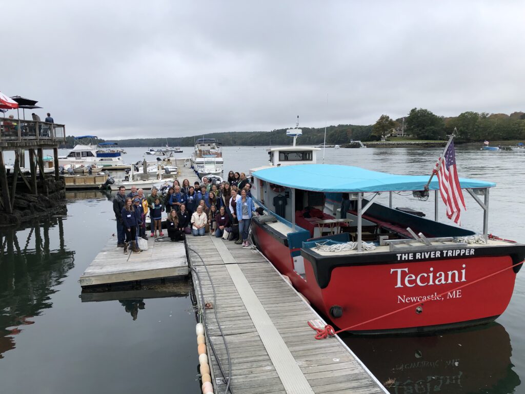 Educator group photo beside tour boat.